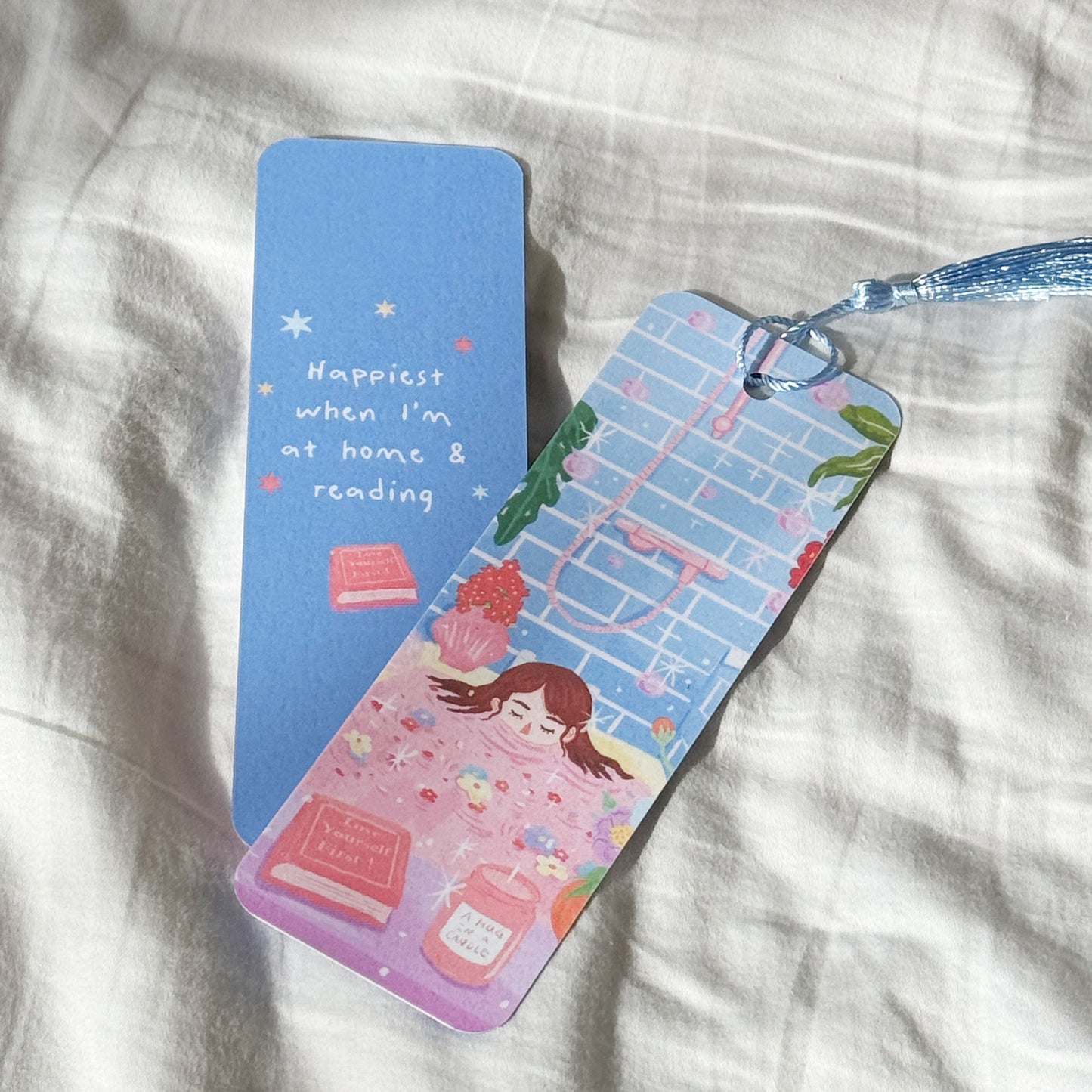 Handmade double-sided bookmark titled “Manifest & Relax,” featuring a cozy self-care illustration on the front and the quote “Happiest when I’m at home & reading” on the back. Matte finish with optional tassel.