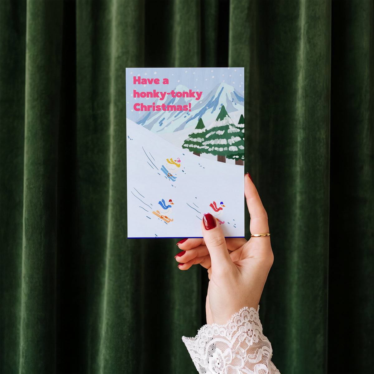 Honky Tonky Christmas card held in hand against a green velvet curtain backdrop