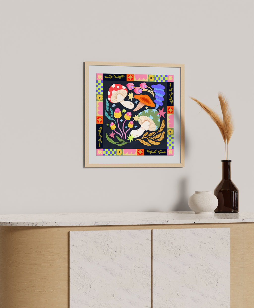 A framed art print featuring a colorful folk-art style illustration of two figures in a floral scene, displayed on a light gray wall above a wooden cabinet with decorative vases.