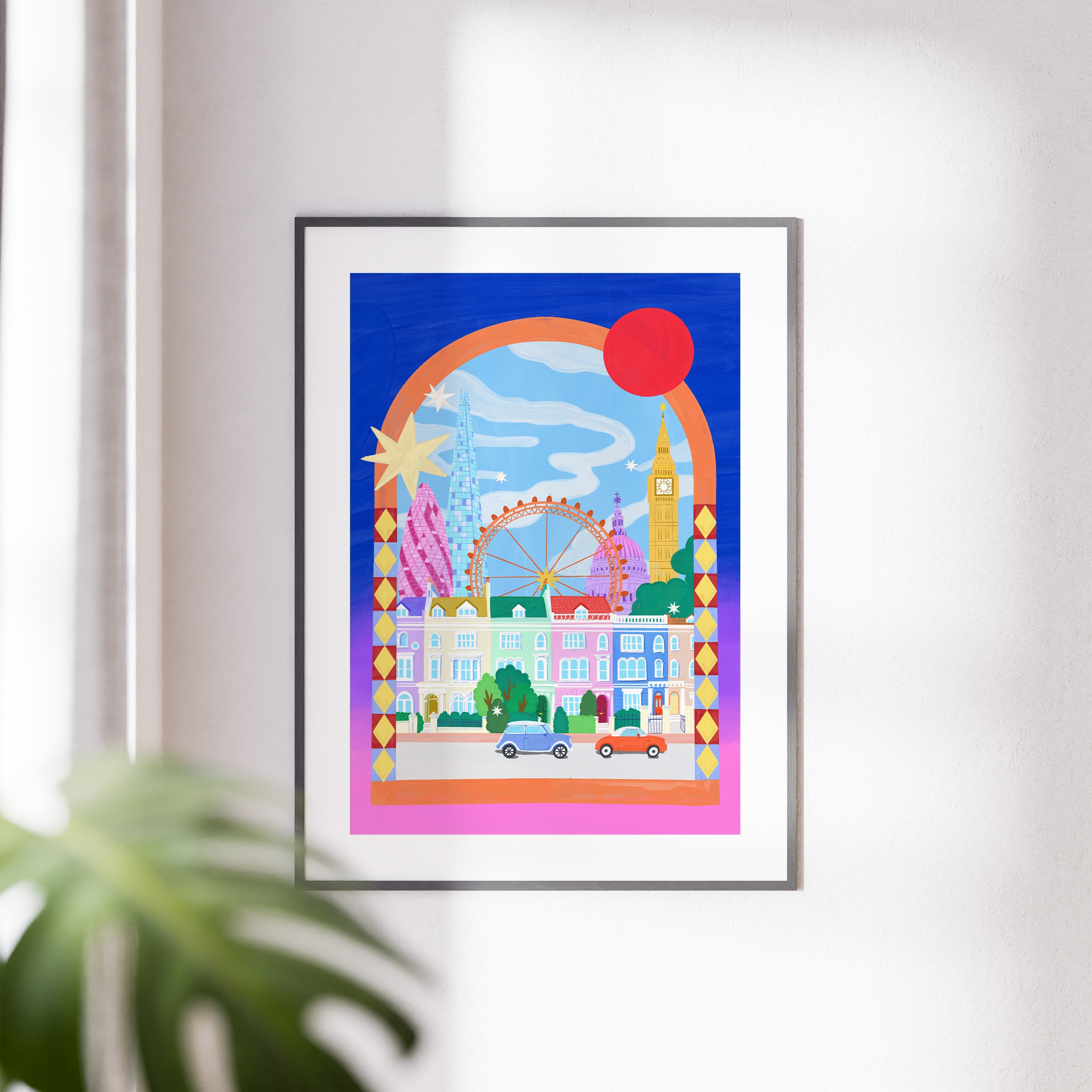 Framed artwork of a colorful cityscape with landmarks on a white wall.