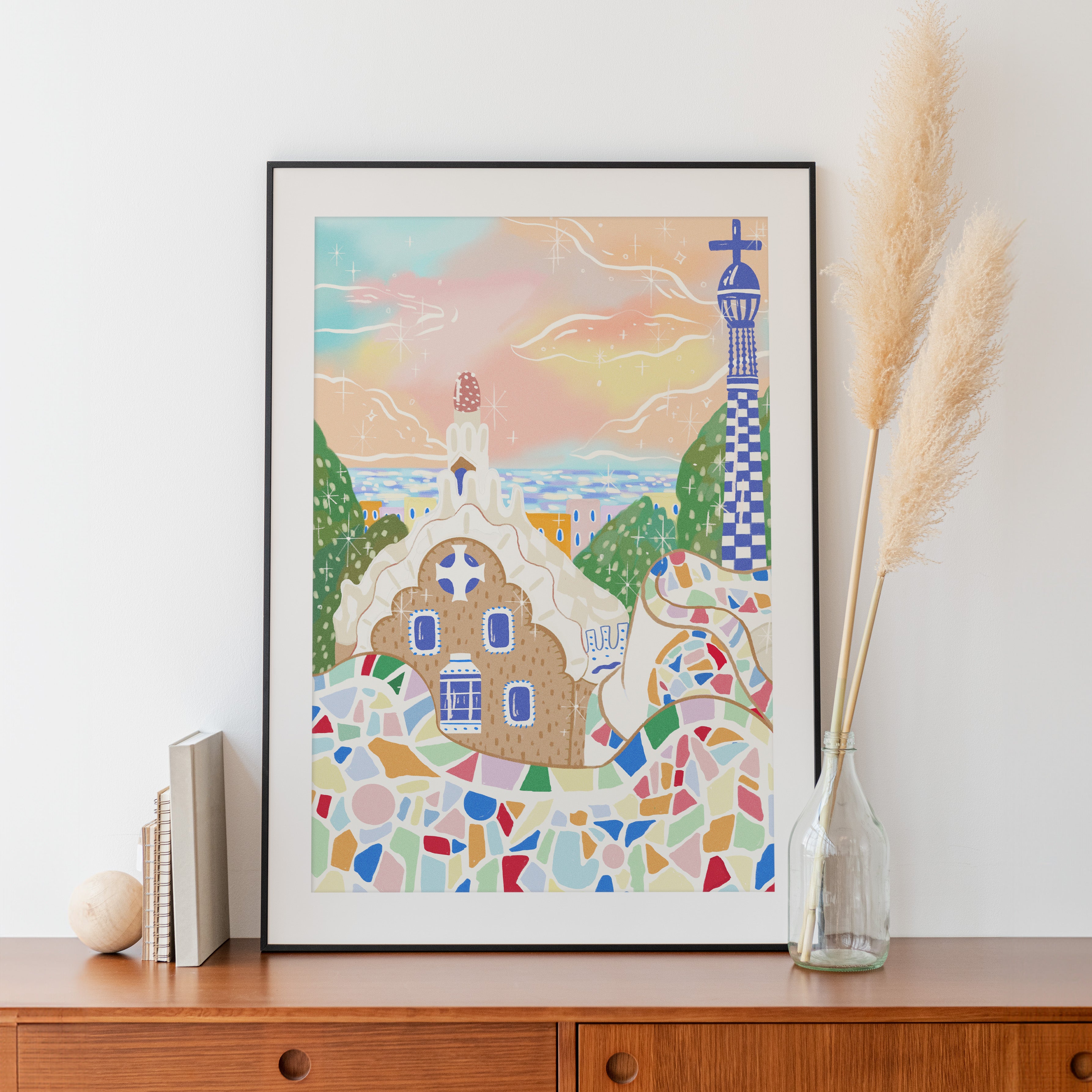 Framed Barcelona art print displayed on interior wall, showcasing colorful Park Güell-inspired mosaic design in a cozy home setting.