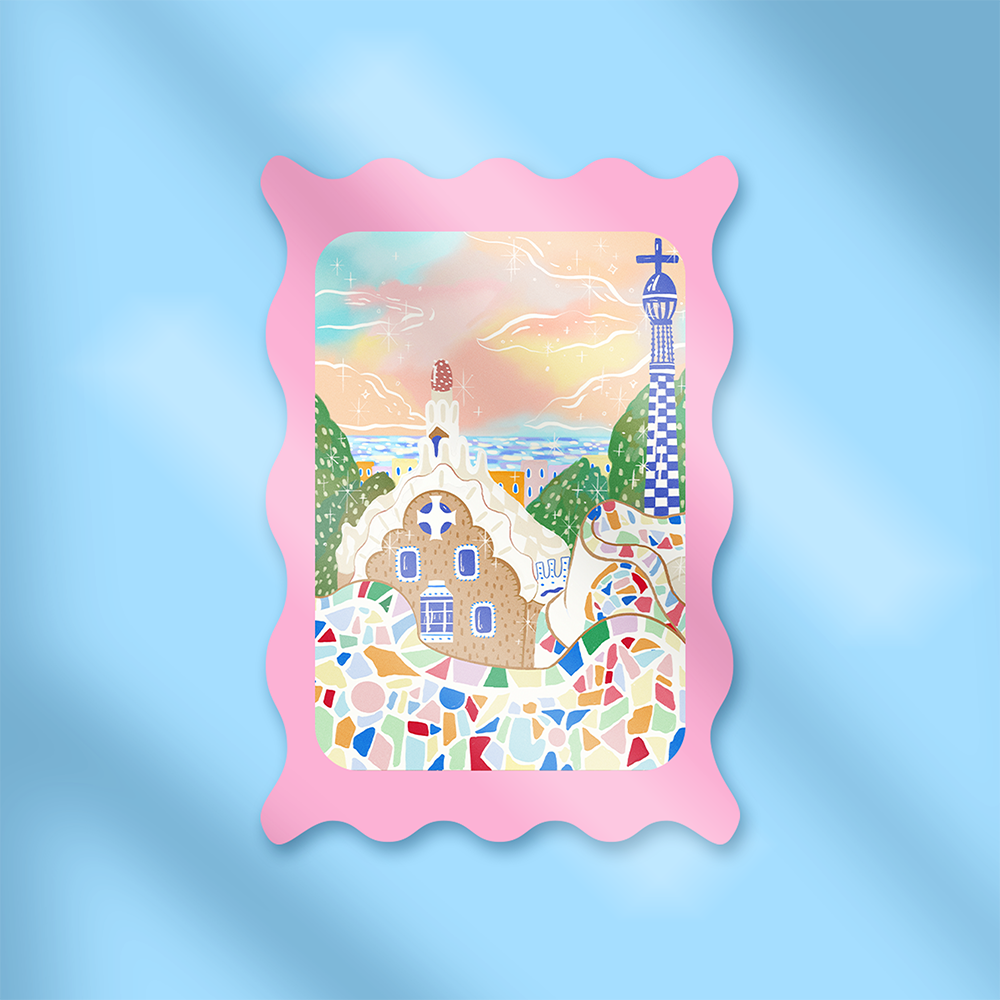 Mini hand holding a pastel pink stamp-style Barcelona sticker featuring Park Güell mosaic tiles and whimsical architecture, against a light blue background.