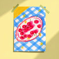Bowl of Cherries art print taped to yellow wall showing red cherries on oval plate with blue gingham background, limited edition print by Ziyi Studio London