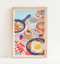 Framed artwork of a breakfast scene with pancakes, eggs, and coffee on a white wall.