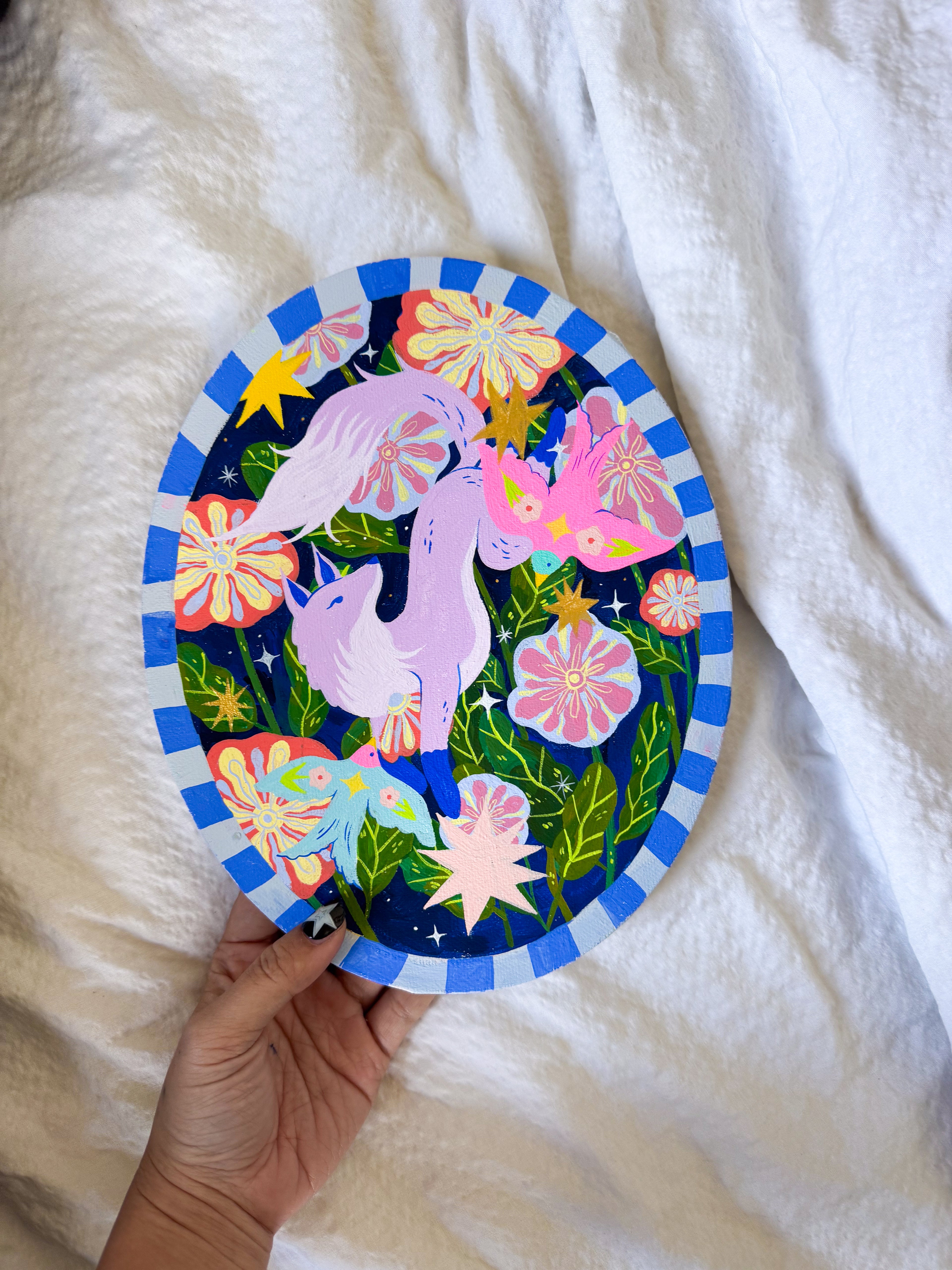Colorful plate with unicorn design held by a hand on a white fabric background