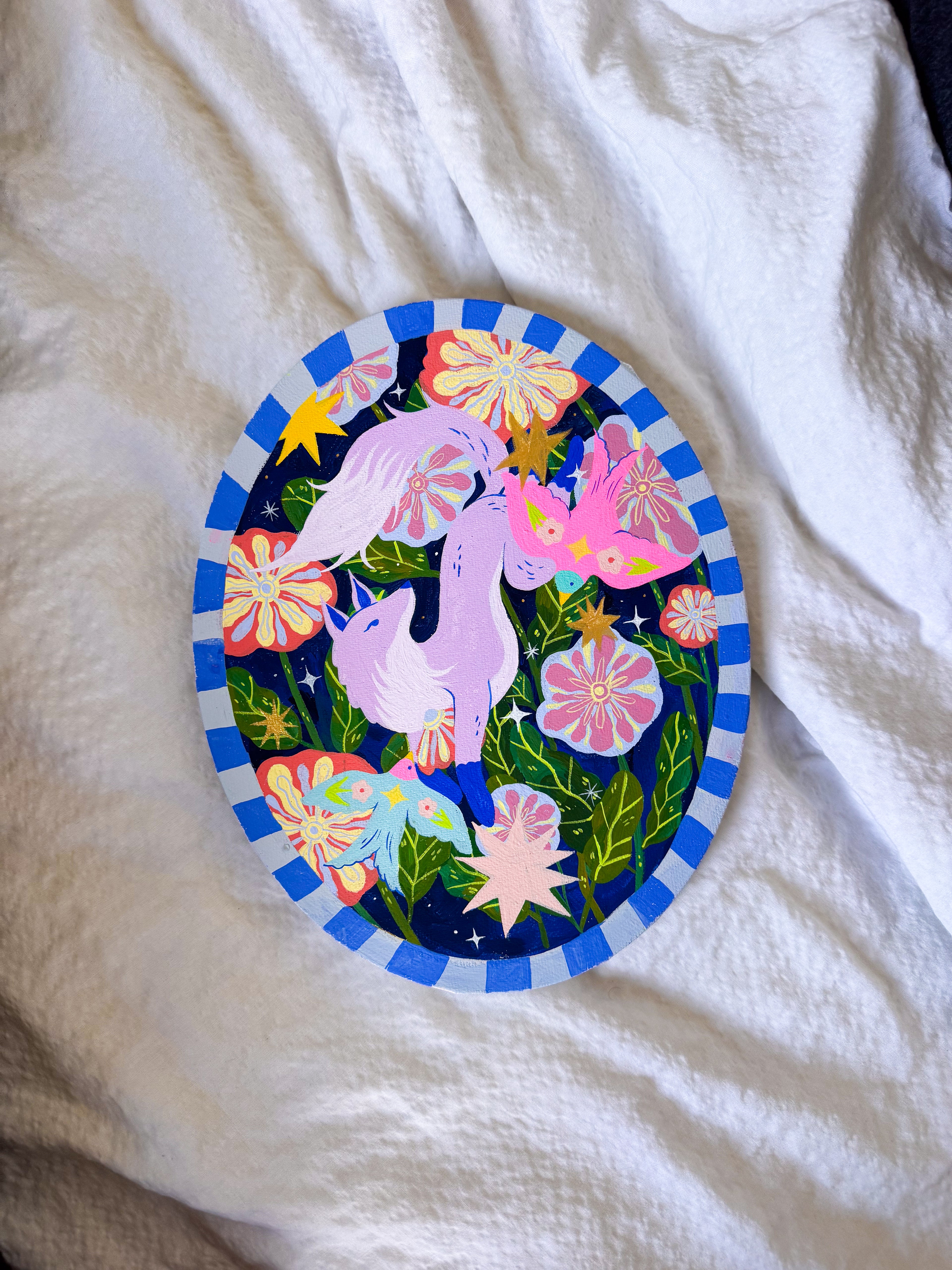 Colorful circular design with unicorns and flowers on a white fabric background