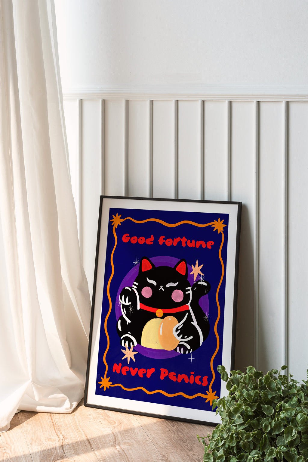 Framed artwork with a black cat holding a pumpkin and text 'Good fortune Never Panics' on a white wall.