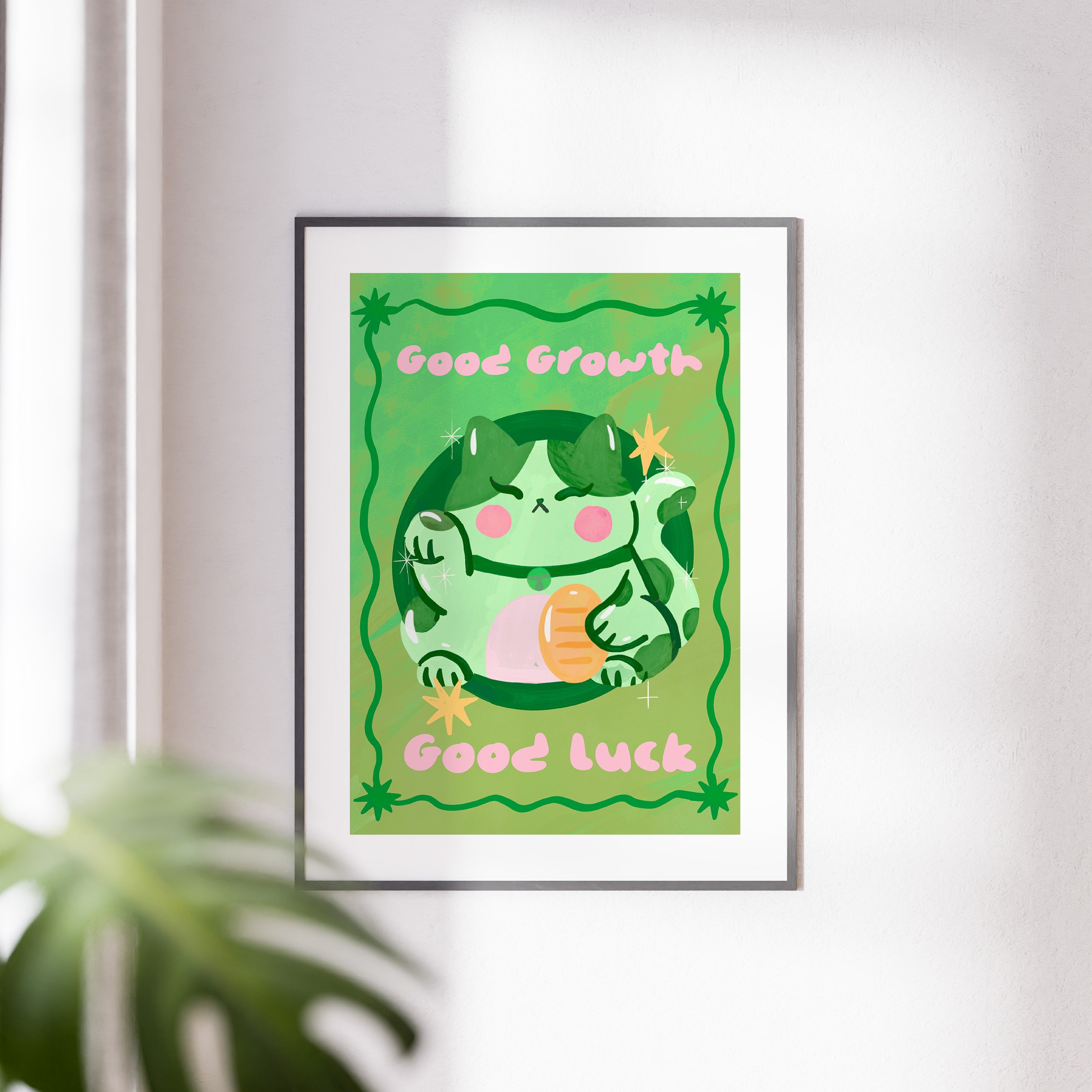 Framed artwork with a green character and text 'Good Growth' and 'Good Luck' on a light background.