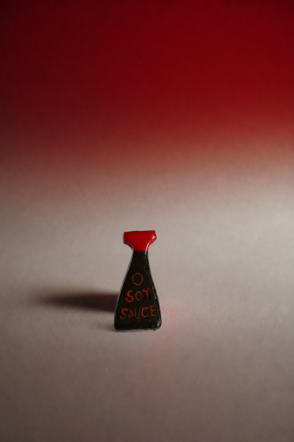 A small novelty pin shaped like a hot sauce bottle, featuring a black body with orange text reading 'O SCOT SMICE' and a red cap, set against a red-to-gray gradient background.