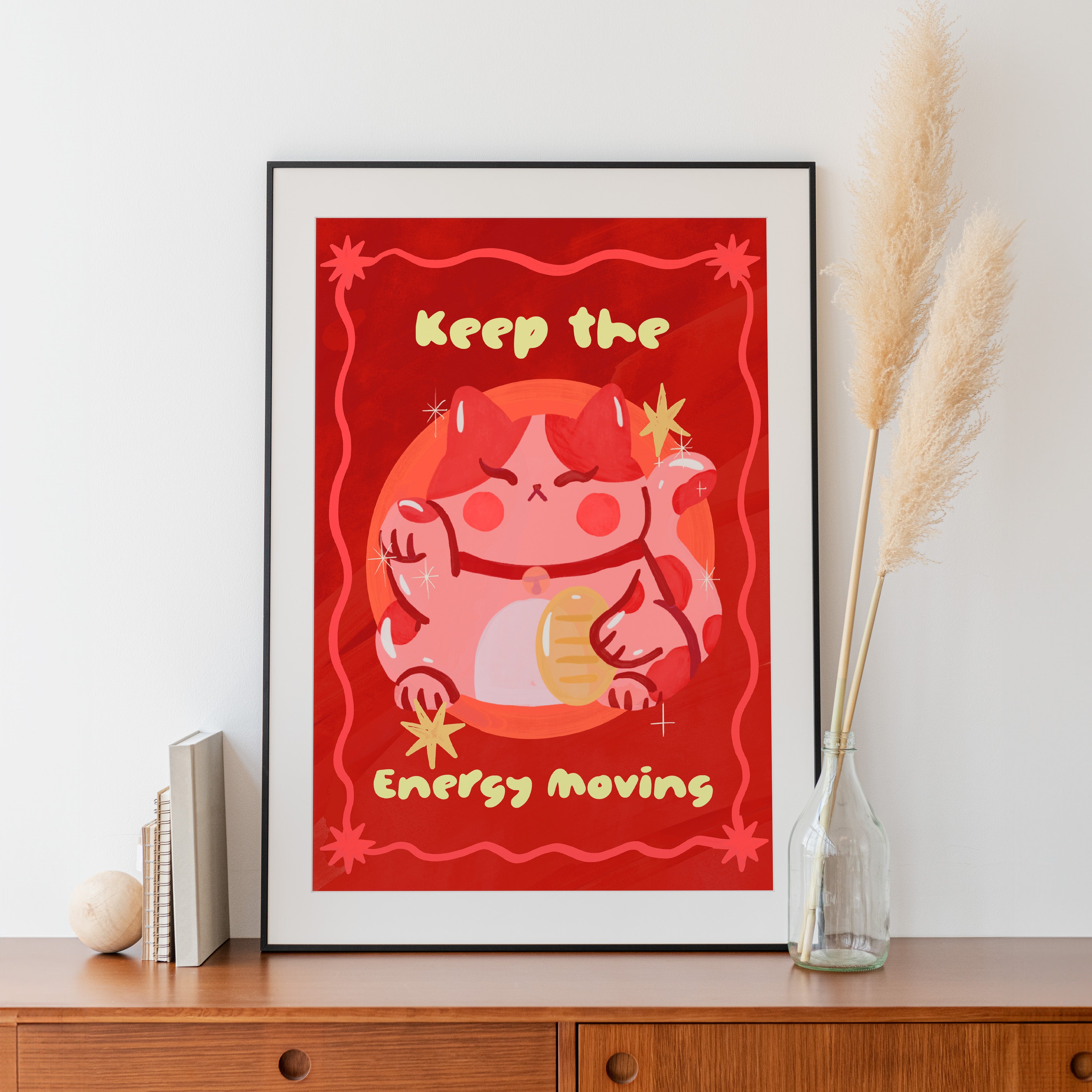 Framed artwork with a red background and cartoon character, placed on a wooden surface.