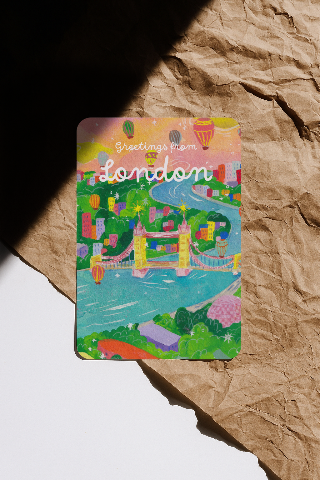 Colorful postcard with 'Greetings from London' text on a crumpled brown paper background
