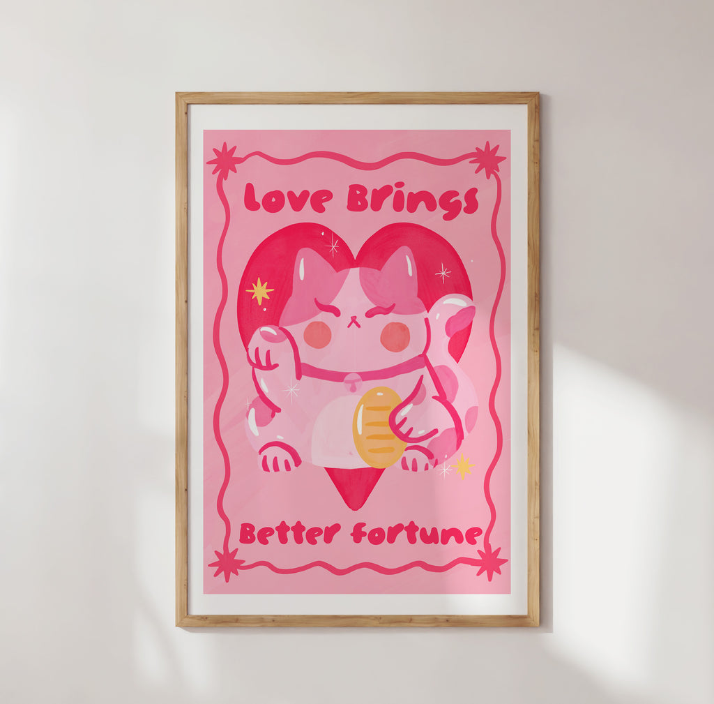 Framed pink poster with cartoon cow and text 'Love Brings Better Fortune' on a white wall.