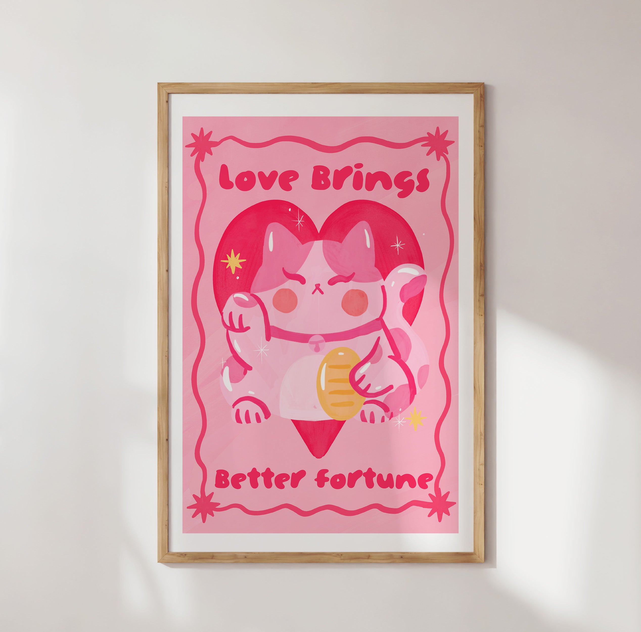 Framed pink poster with cartoon cow and text 'Love Brings Better Fortune' on a white wall.