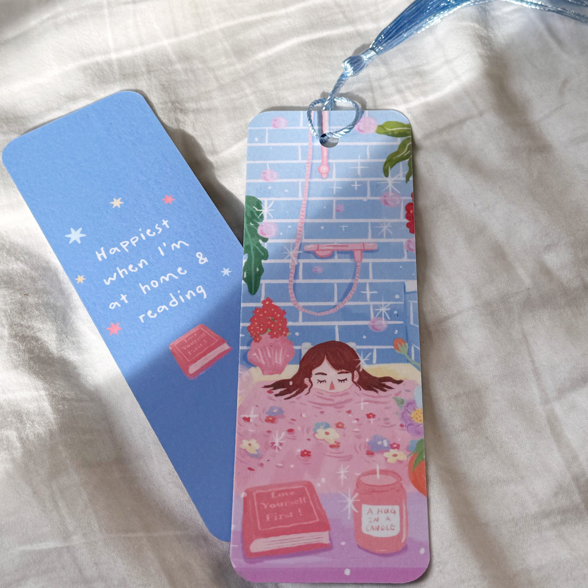Handmade double-sided bookmark titled “Manifest & Relax,” featuring a cozy self-care illustration on the front and the quote “Happiest when I’m at home & reading” on the back. Matte finish with optional tassel.
