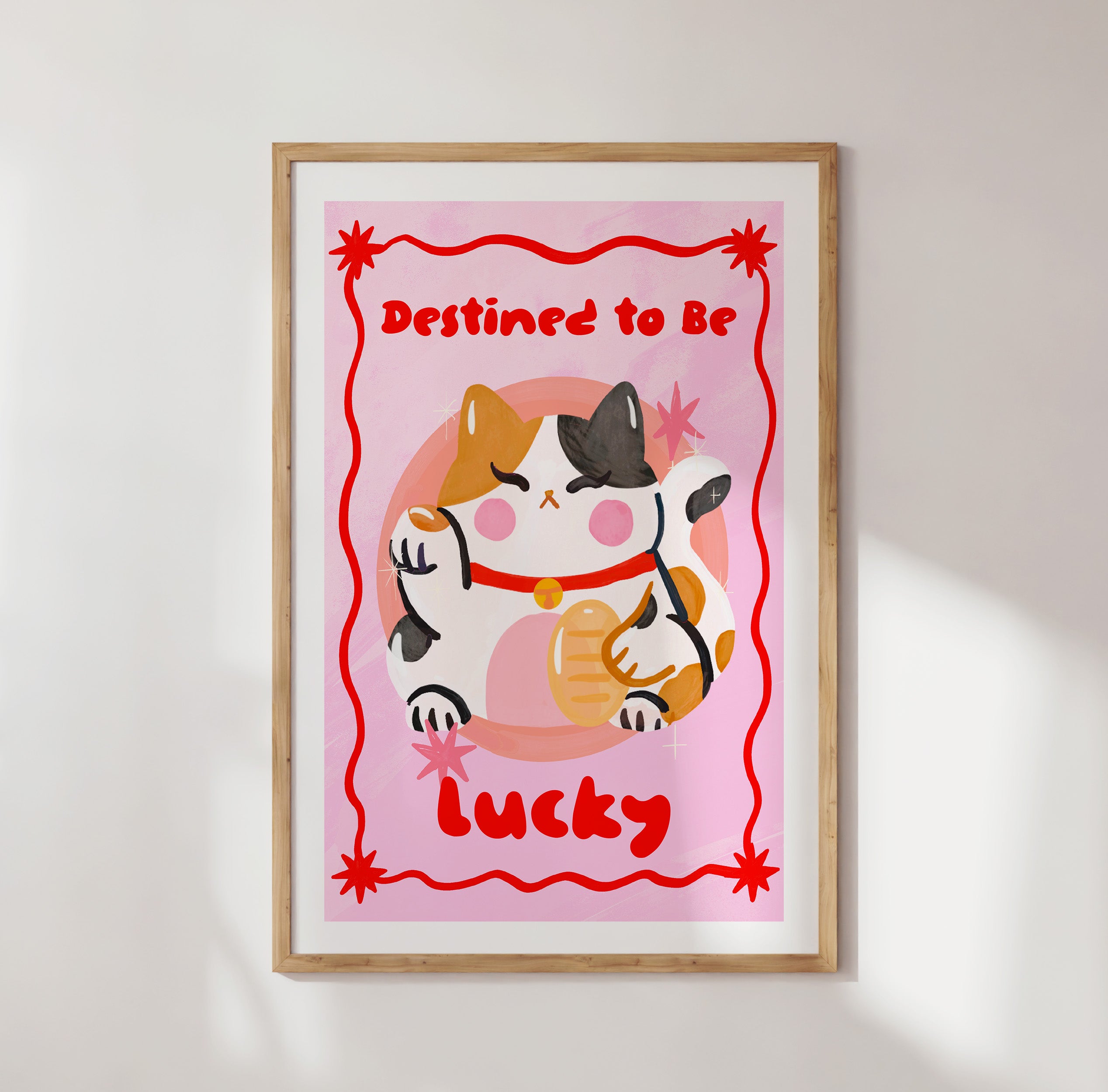 Framed artwork with a cat illustration and text 'Destined to be lucky' on a pink background.