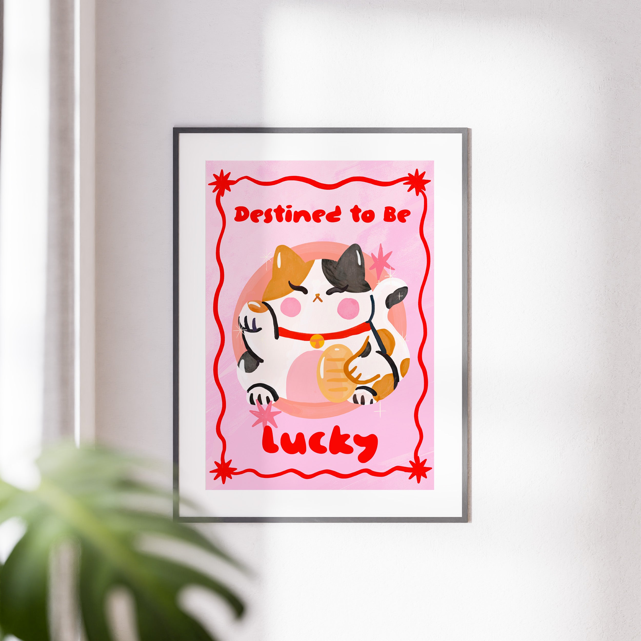 Framed artwork with a cat illustration and text 'Destined to be lucky' on a pink background.