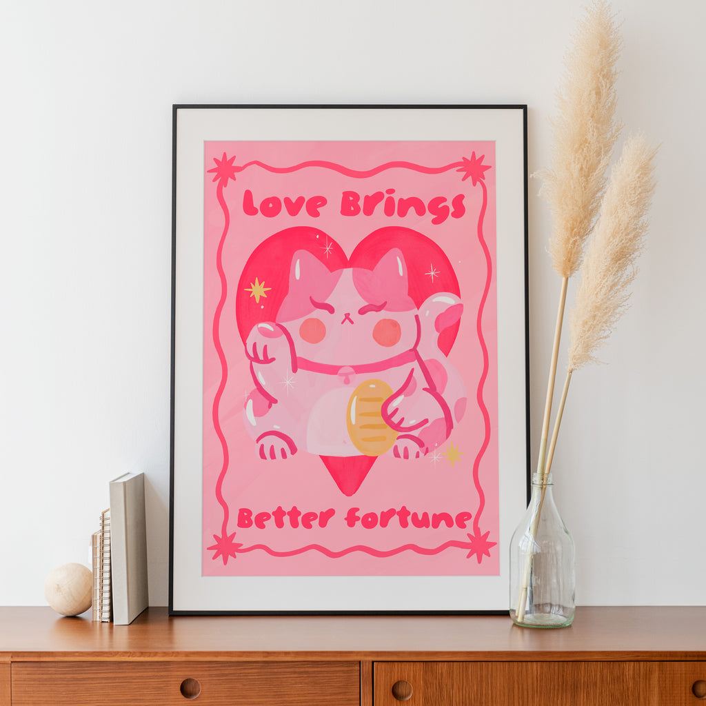 Framed pink artwork with cat illustration and text on a wooden surface.