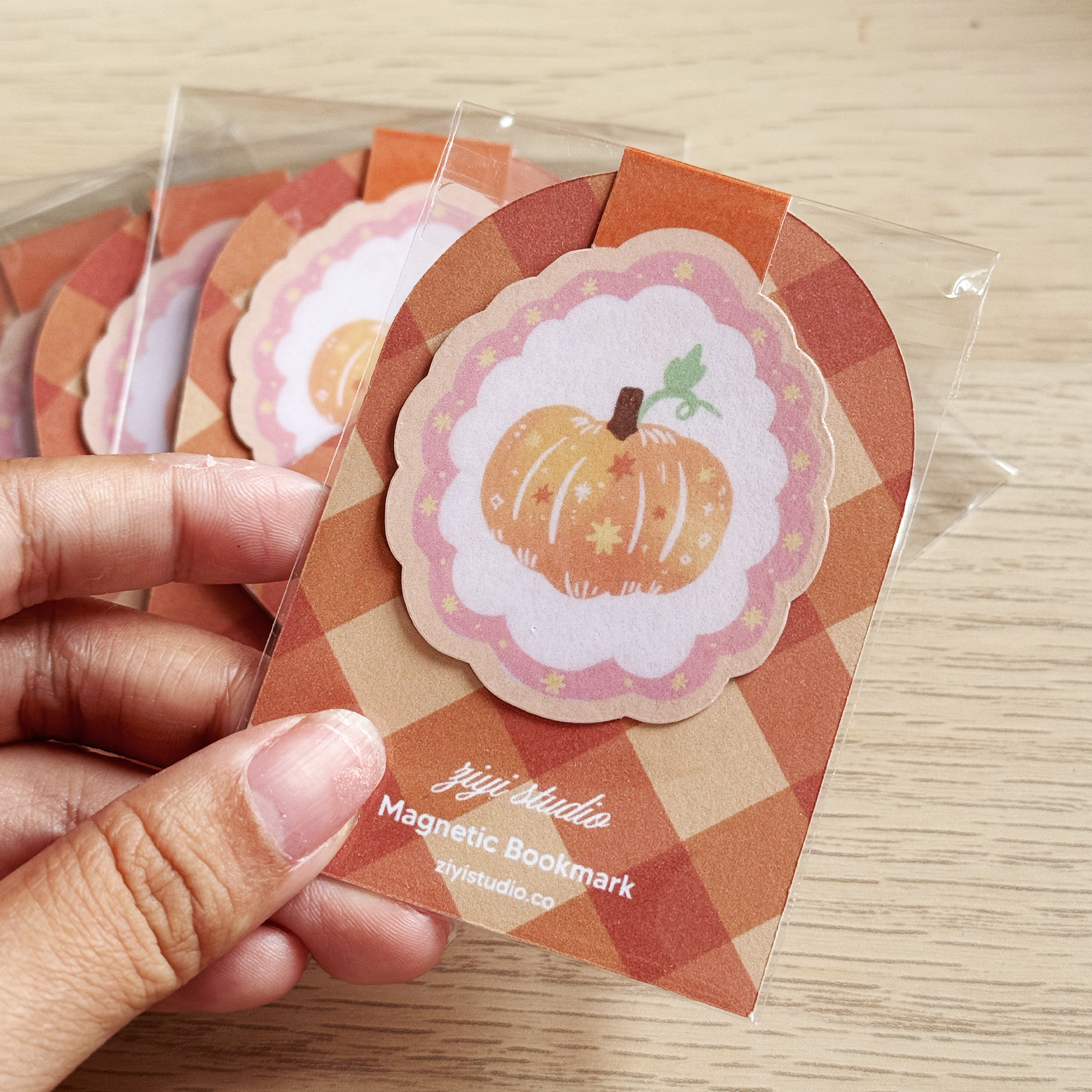 Magnetic bookmark with pumpkin design held by a hand, brand 'ziji studio' visible