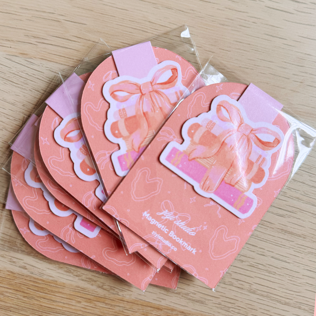 Set of pink magnetic bookmarks with decorative designs on a wooden surface