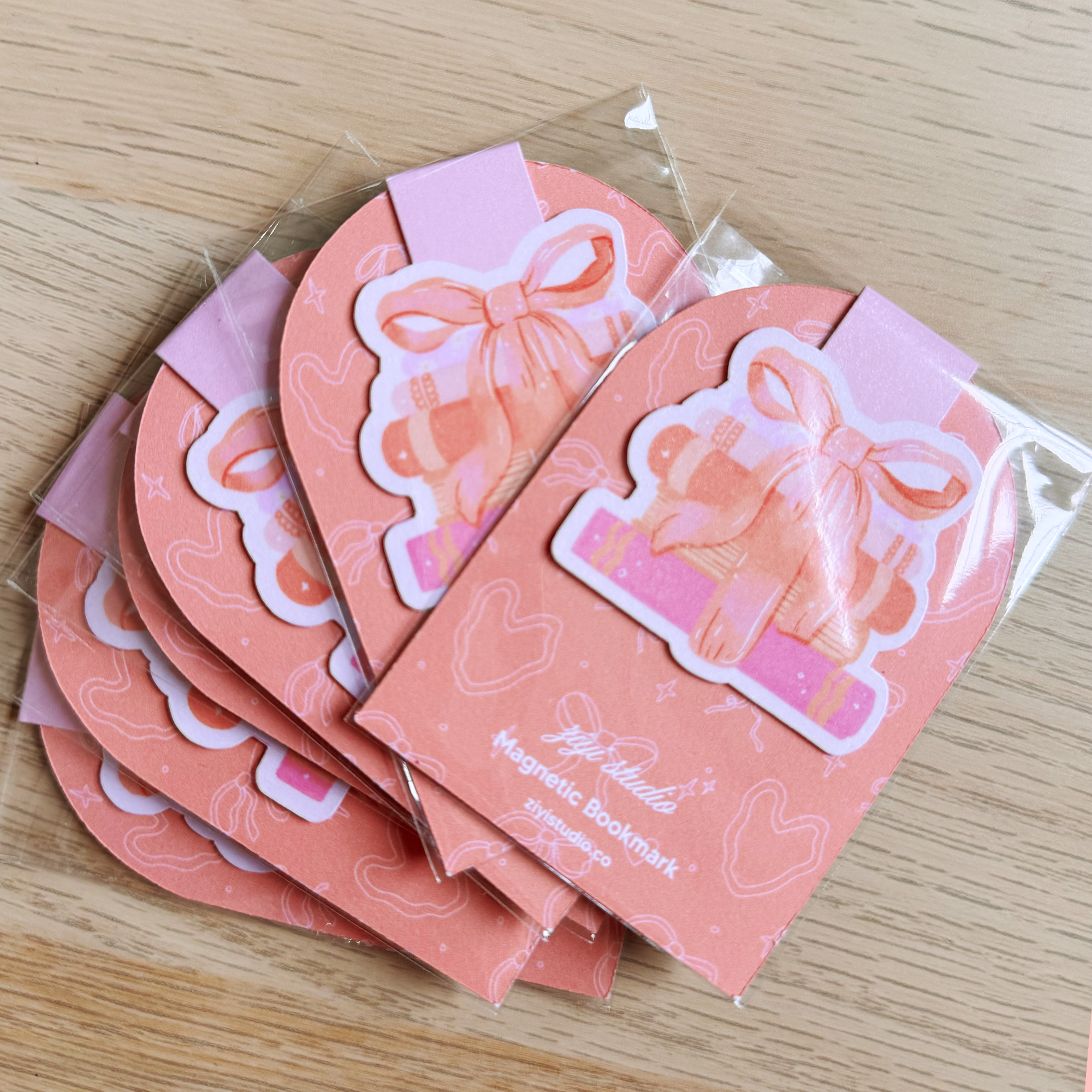 Set of pink magnetic bookmarks with decorative designs on a wooden surface