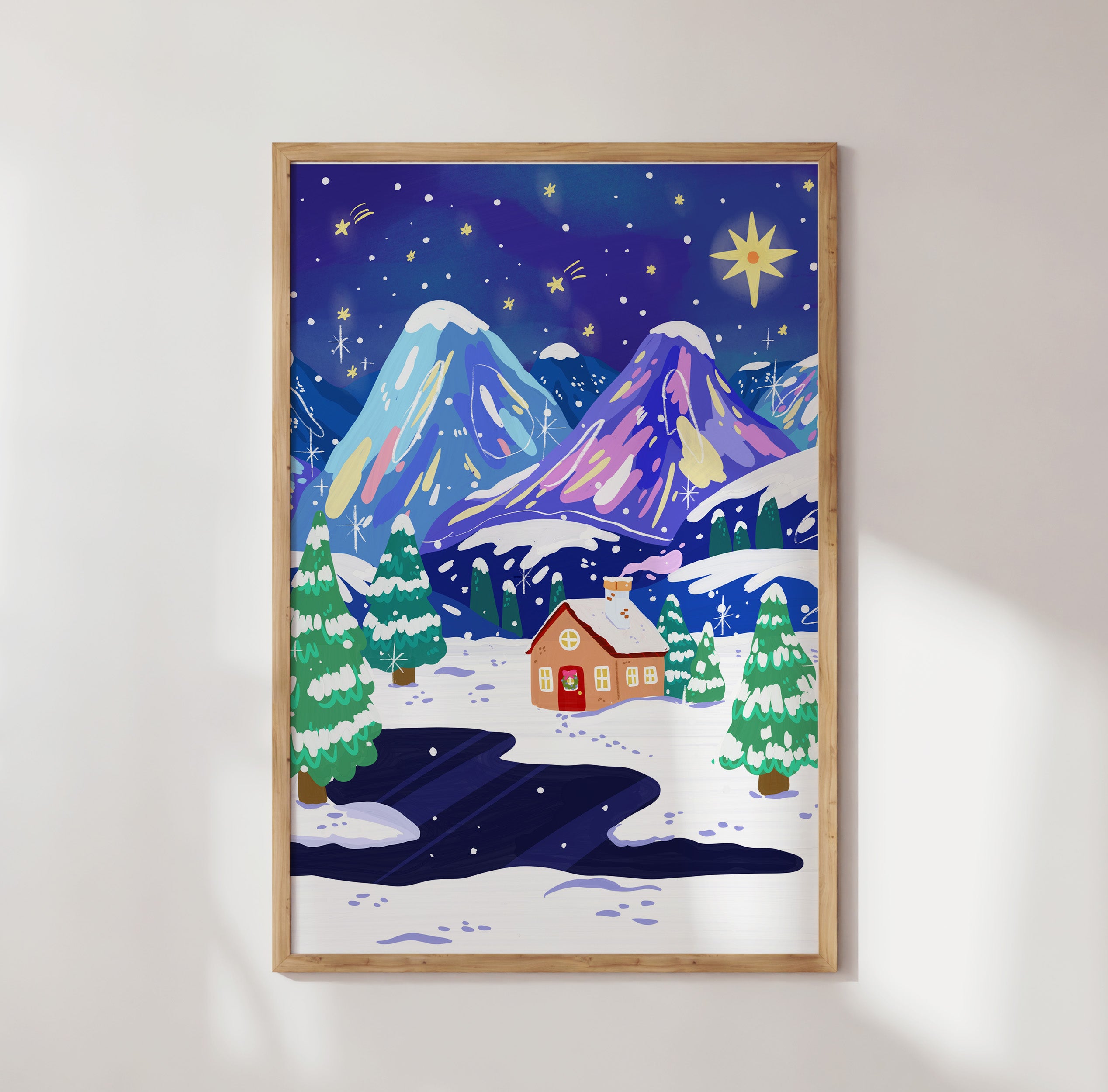 Framed artwork of a winter landscape with mountains and a house on a white wall.