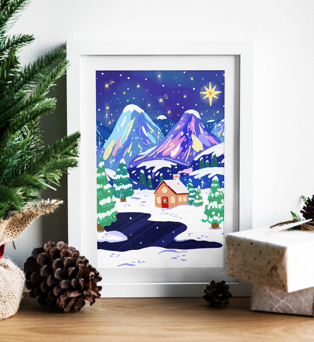 Framed winter scene print with mountains and a house, surrounded by Christmas decor.