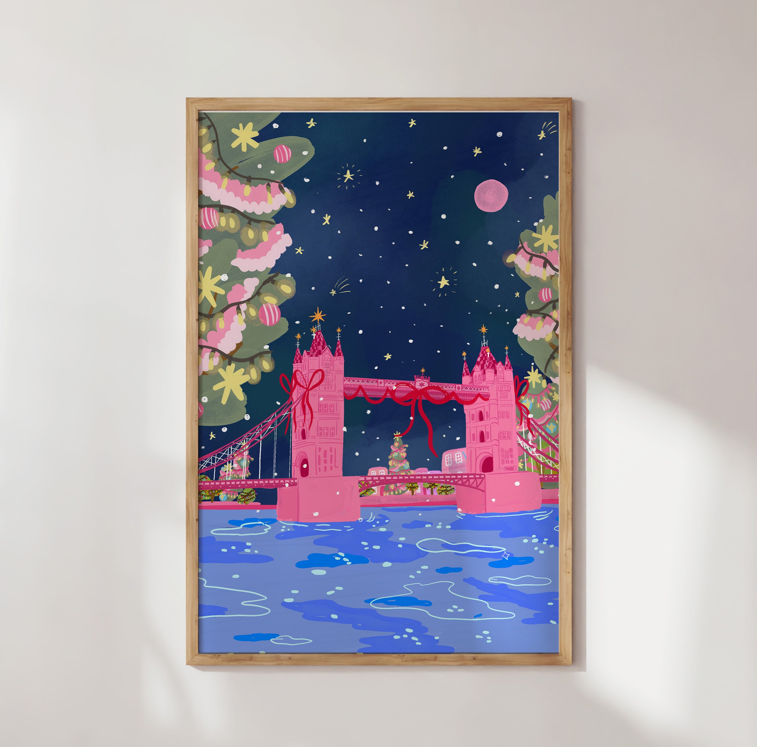Framed artwork of a pink London Bridge with festive decorations on a white wall.