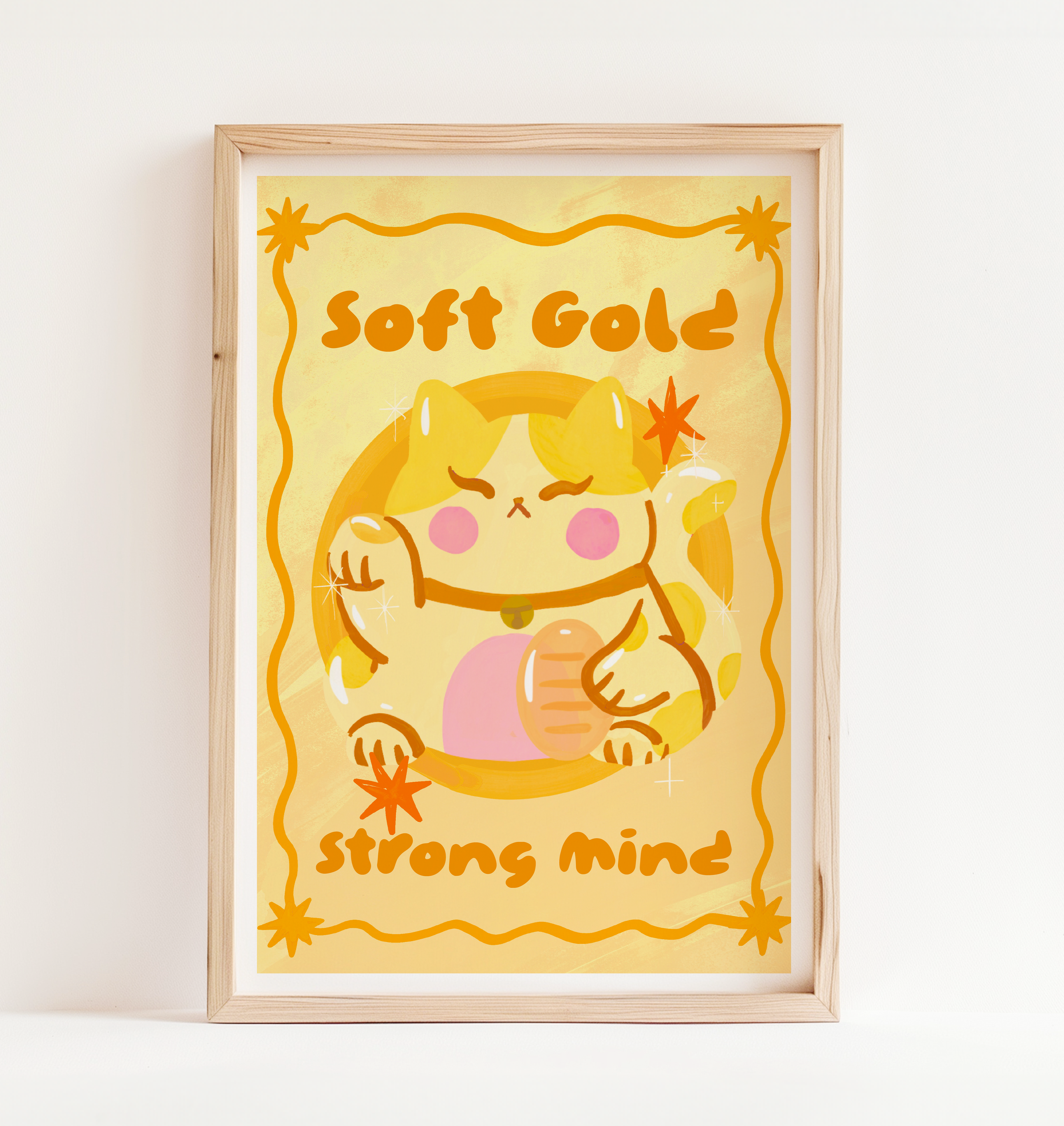 Framed artwork with a cartoon cat character and text 'Soft Gold Strong Mind' on a yellow background.