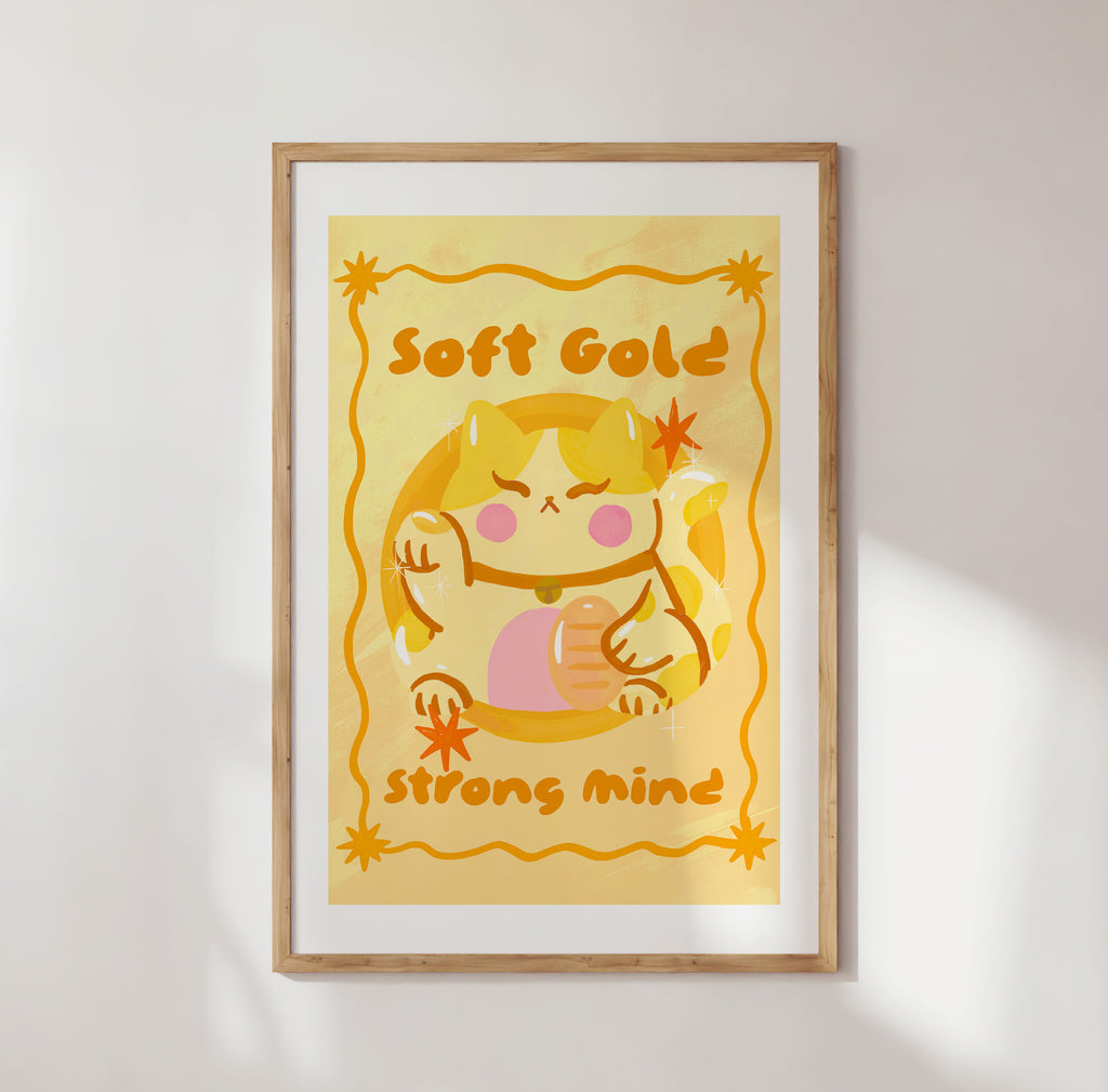 Framed artwork with a cartoon character and text 'Soft Gold Strong Mind' on a yellow background.
