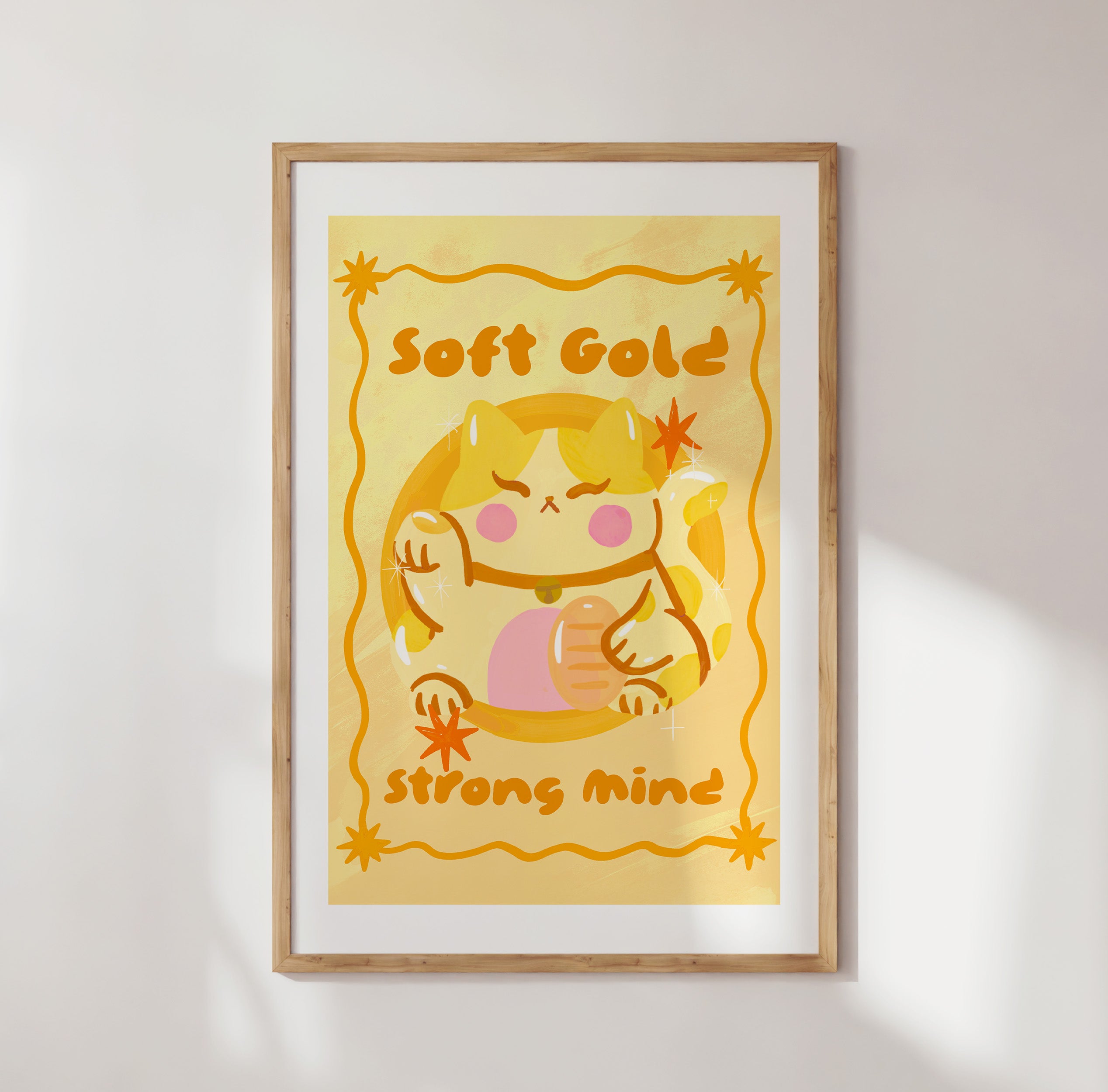 Framed artwork with a cartoon character and text 'Soft Gold Strong Mind' on a yellow background.